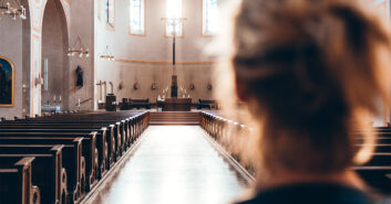 Eine Frau steht in der Kirche und schaut zum Kreuz